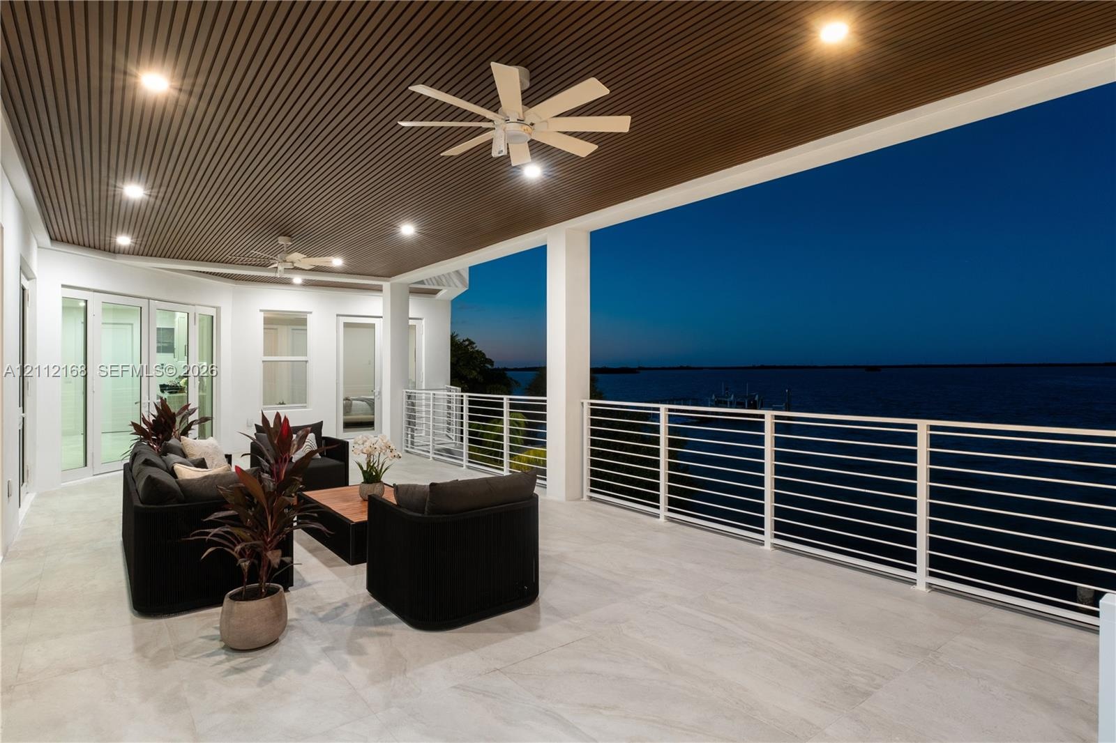 Covered terrace featuring large-format tile flooring, a slatted wood-finish ceiling with recessed lighting, dual ceiling fans, and a white horizontal 