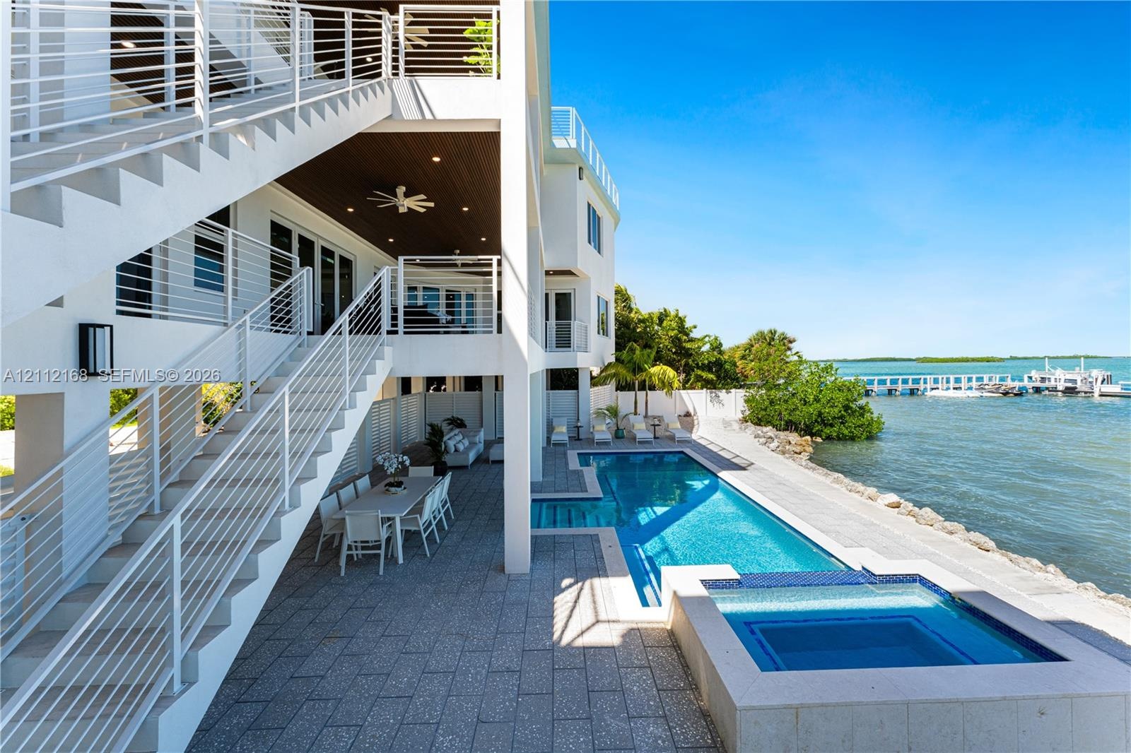 Multi-level exterior featuring a private swimming pool with integrated spa, paved pool deck, metal stair railings, and direct water access with a priv