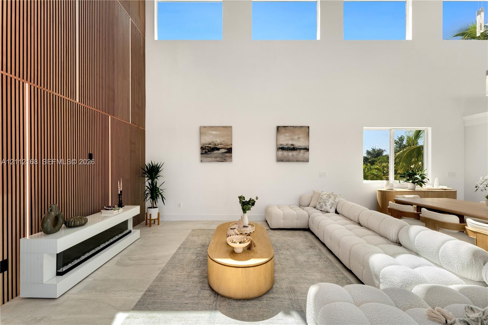 Double-height ceilings with transom windows, full-height vertical wood-slat feature wall, integrated linear fireplace with white floating hearth, and 
