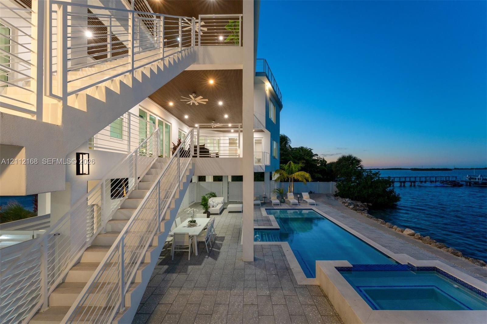 Multi-level exterior featuring white cable-railing staircases, a covered patio with recessed lighting, an in-ground swimming pool, and an attached spa