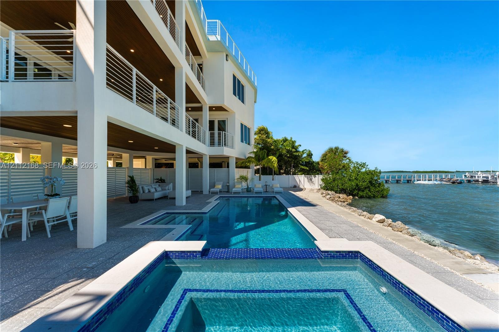Multi-level exterior featuring tiered balconies with metal railings, a covered patio with recessed lighting, an integrated swimming pool and spa, and 