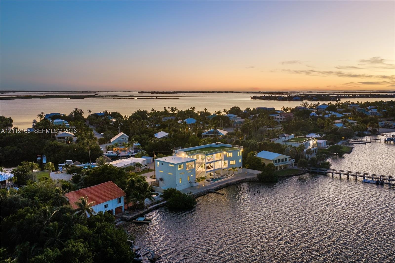 Contemporary multi-story residence featuring expansive floor-to-ceiling glass walls, a private swimming pool, and direct waterfront access