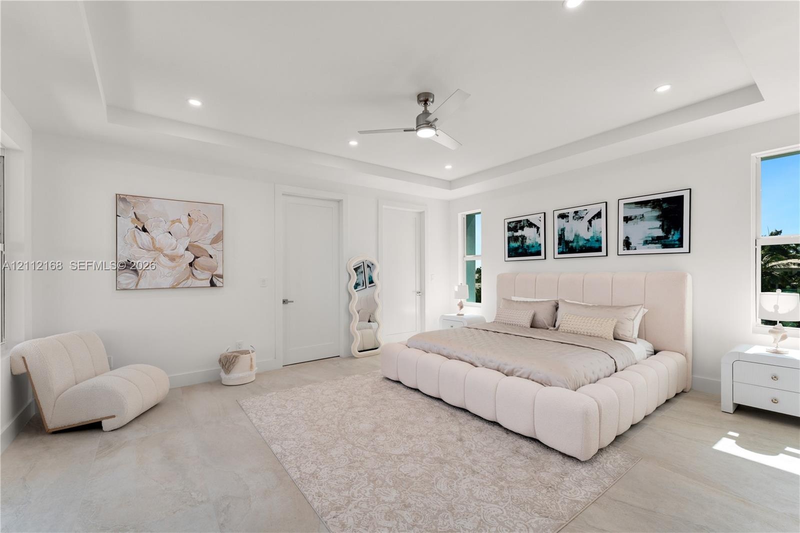 Spacious interior featuring a tray ceiling, recessed lighting, neutral large-format tile flooring, and a modern ceiling fan