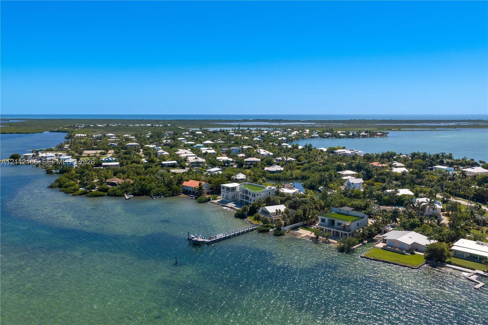Aerial perspective of waterfront property featuring an extended deep-water dock, direct shoreline access, and expansive coastal surroundings