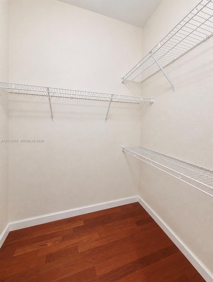 Storage area featuring wood-finish flooring and tiered white wire shelving