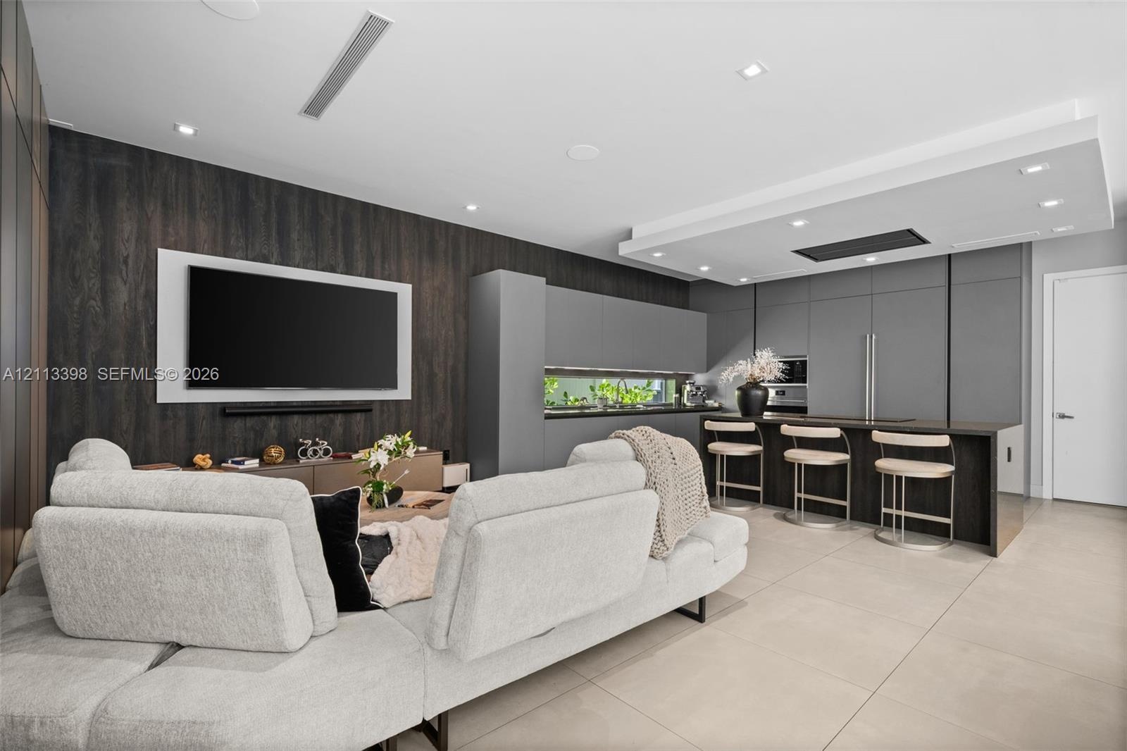 Modern kitchen featuring matte grey flat-panel cabinetry, integrated appliances, a dark wood-finish island with breakfast bar seating, recessed ceilin