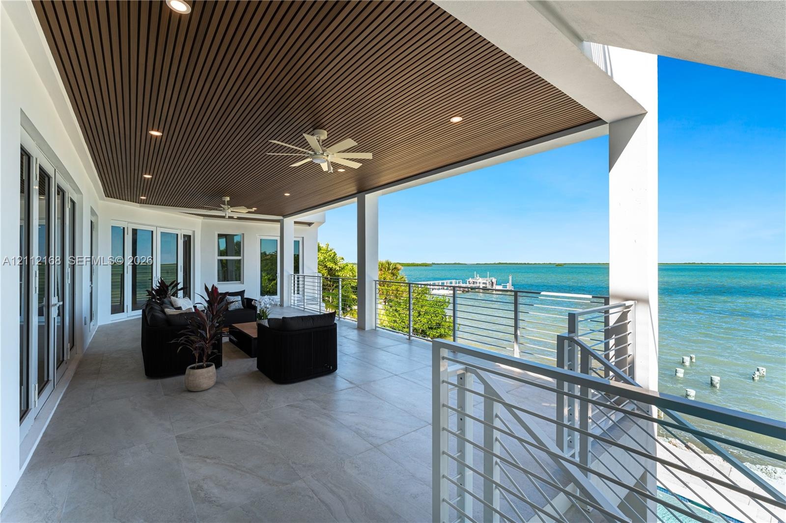 Covered terrace featuring large-format tile flooring, a slatted wood-finish ceiling, recessed lighting, ceiling fans, and a cable railing system