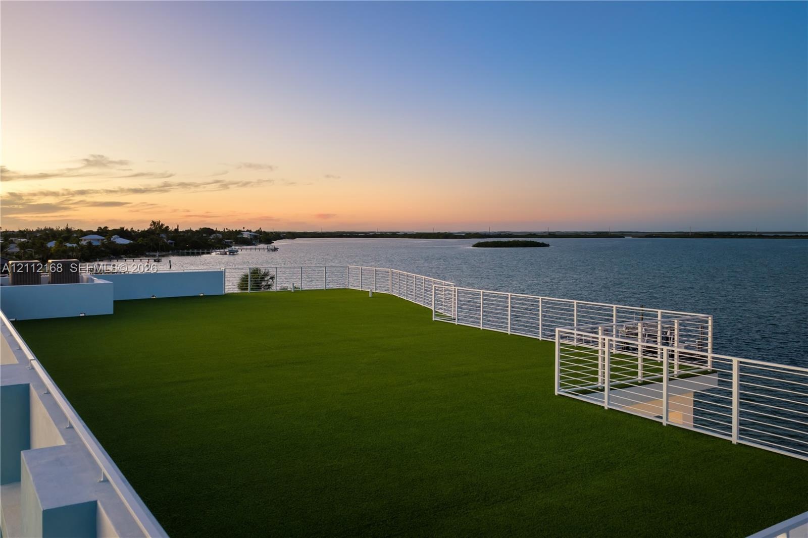 Expansive rooftop terrace featuring synthetic turf flooring and horizontal cable railing