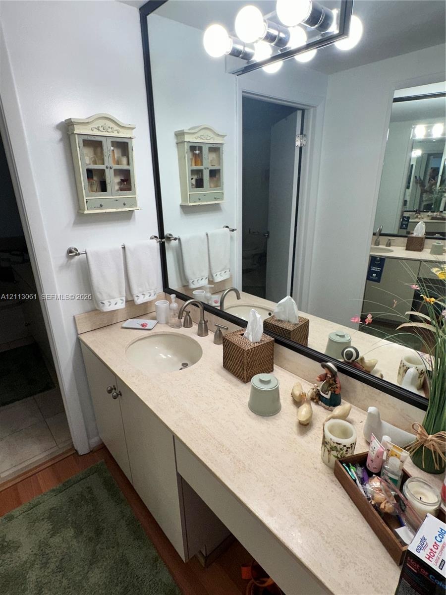 Bathroom vanity featuring a solid-surface countertop, an integrated oval sink, a brushed metal faucet, a full-width mirror with a black frame, and a m