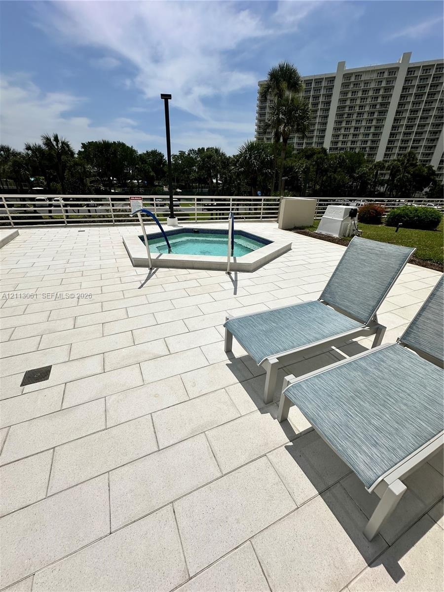 Elevated terrace featuring a paved stone deck, an in-ground spa, and a perimeter safety railing