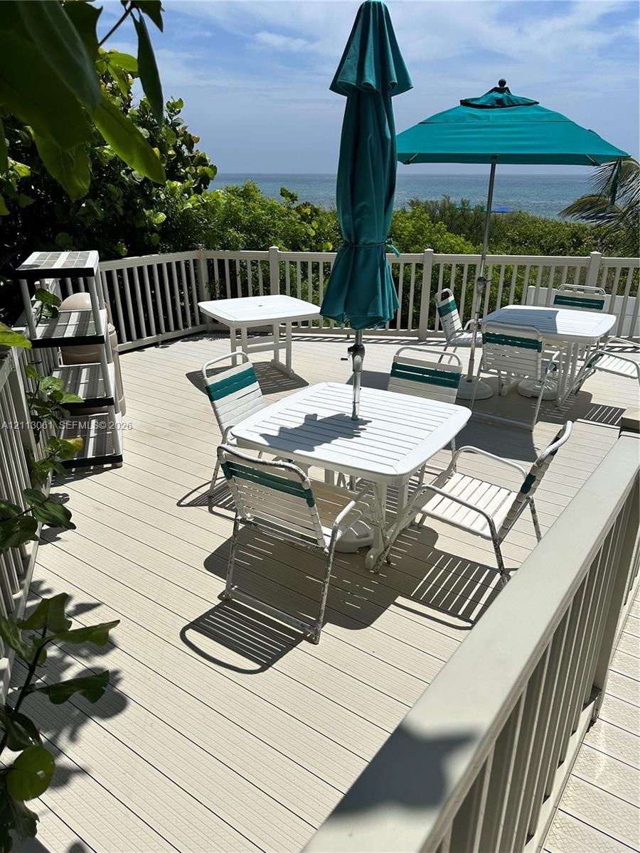 Elevated exterior deck featuring light-toned composite decking, white vertical balustrade railing, and an unobstructed ocean backdrop