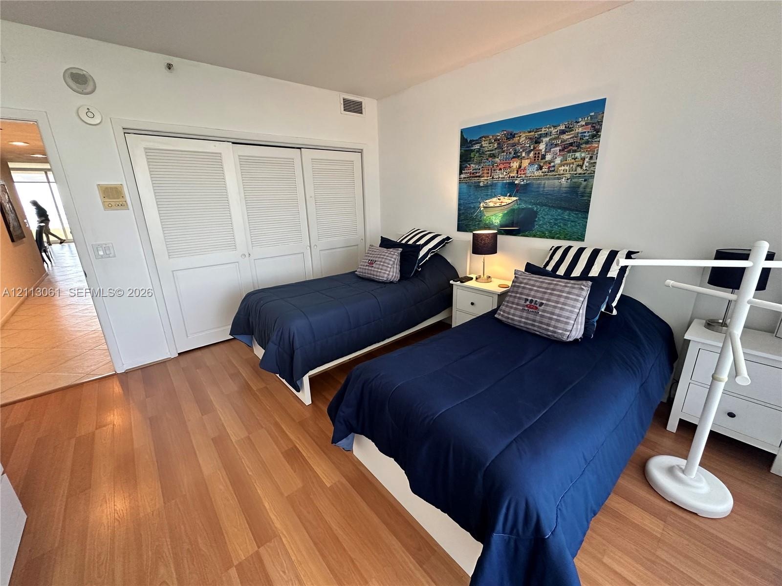 Wood-finish flooring and floor-to-ceiling white louvered closet doors