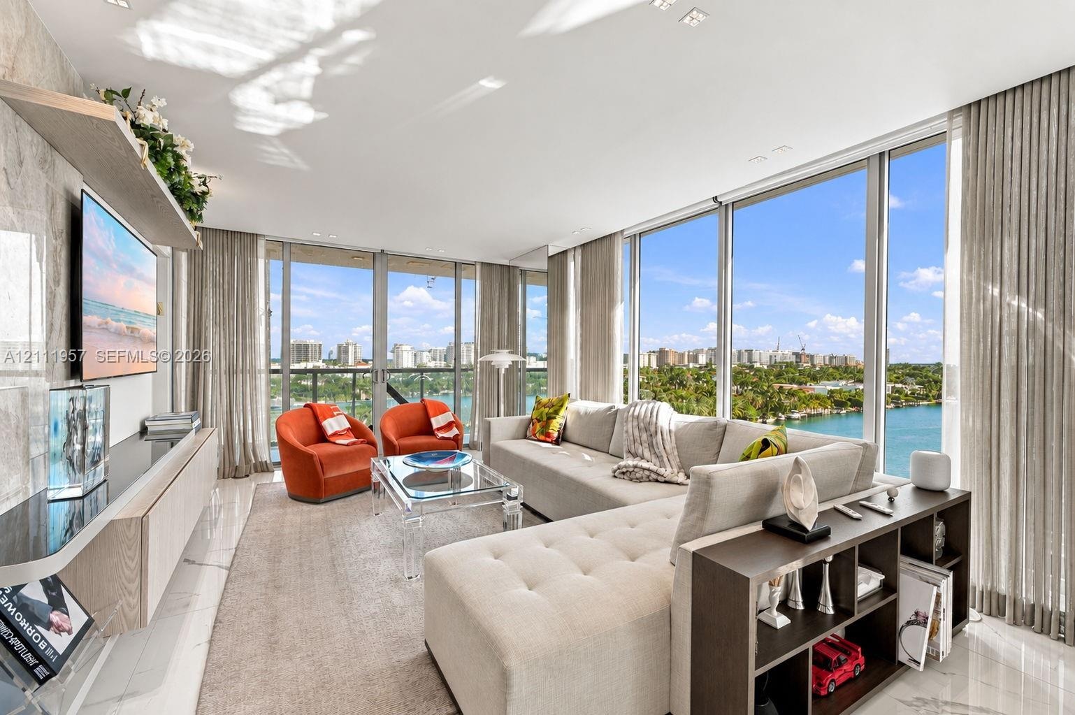 Floor-to-ceiling glass windows, stone-finish flooring, and a wall-mounted light-wood cabinetry unit