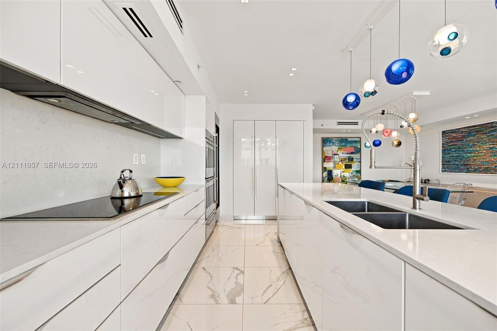 Contemporary kitchen featuring high-gloss cabinetry, quartz countertops, large-format veined tile flooring, a stainless steel double-basin sink with p