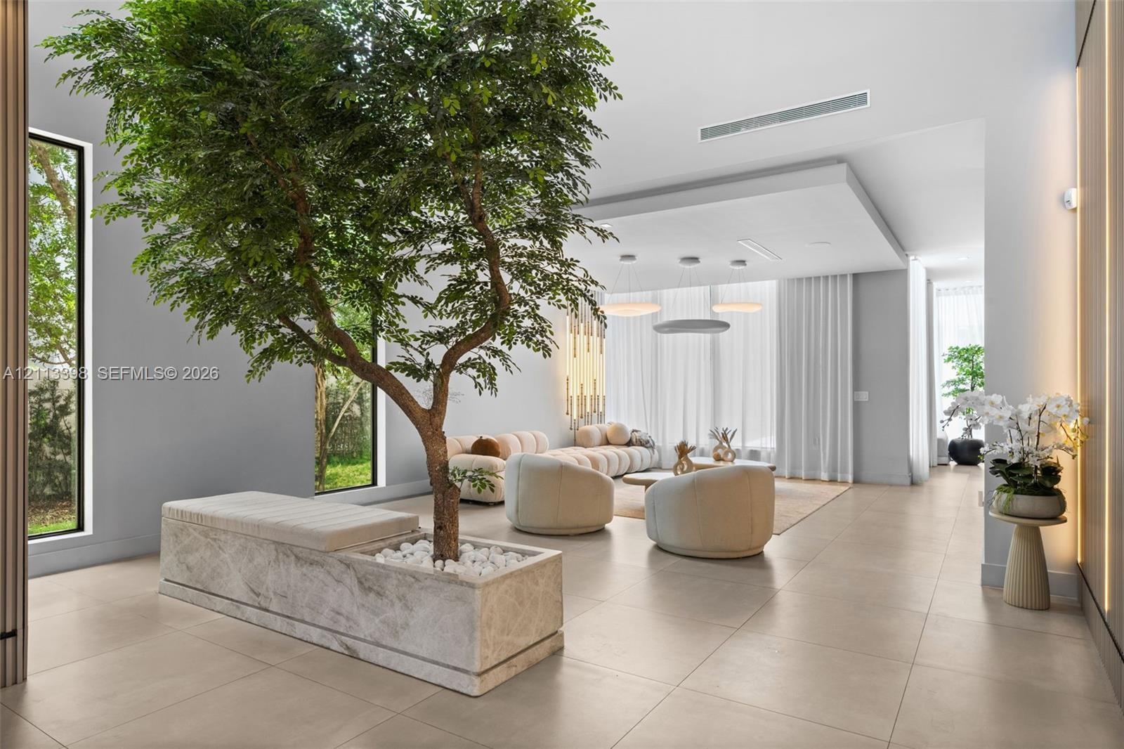 Interior space featuring large-format tile flooring, a recessed ceiling with integrated lighting, floor-to-ceiling windows, and a built-in stone plant