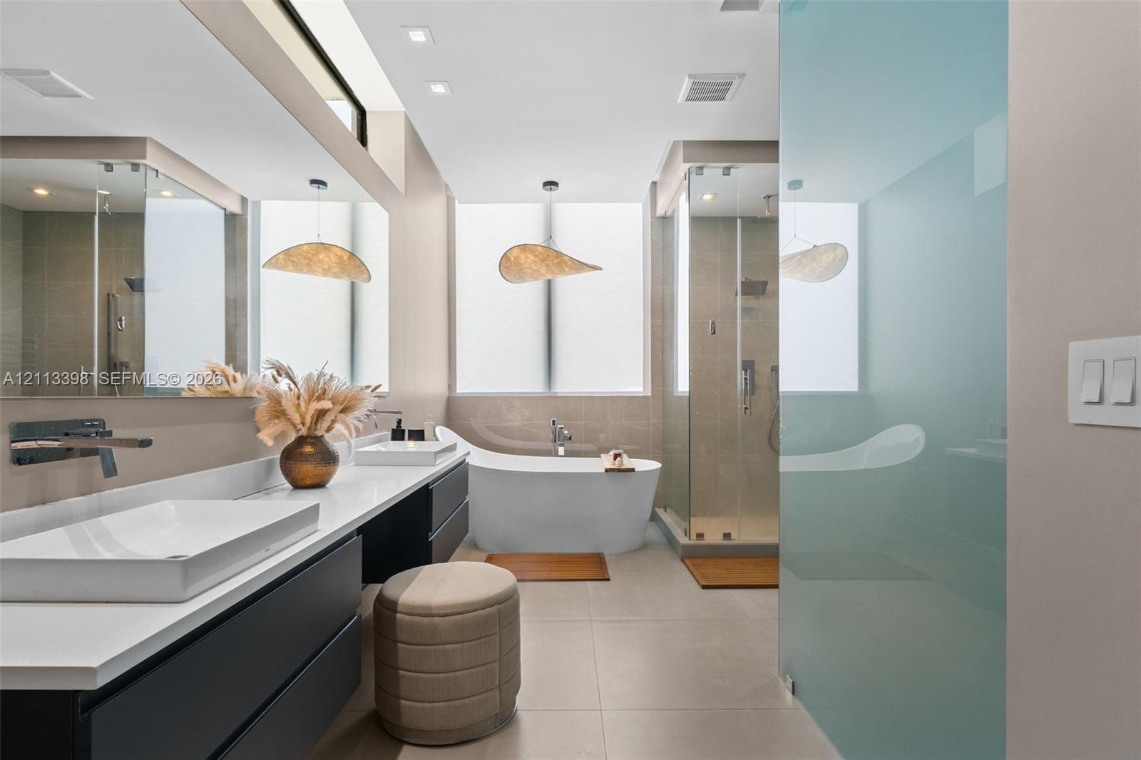 Modern bathroom featuring a floating dual vanity with rectangular vessel sinks, wall-mounted faucets, a freestanding soaking tub, and a glass-enclosed