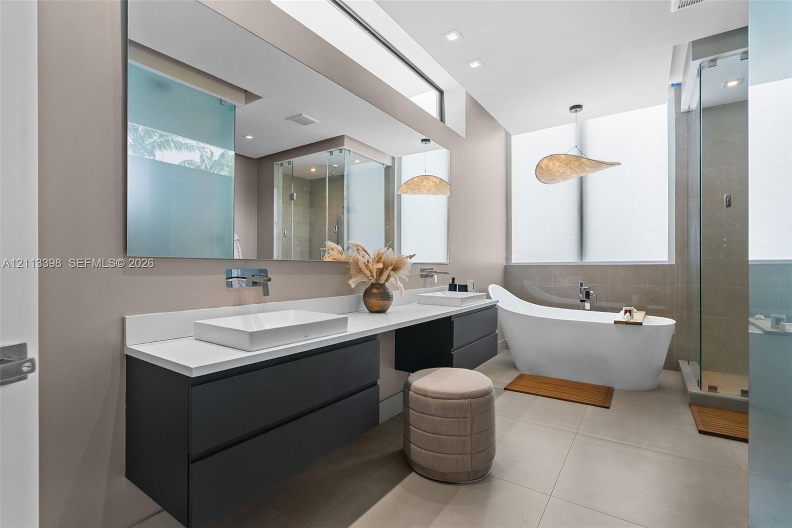 Floating dual-vanity with rectangular vessel sinks, quartz countertop, wall-mounted faucets, freestanding soaking tub, and glass-enclosed shower with 