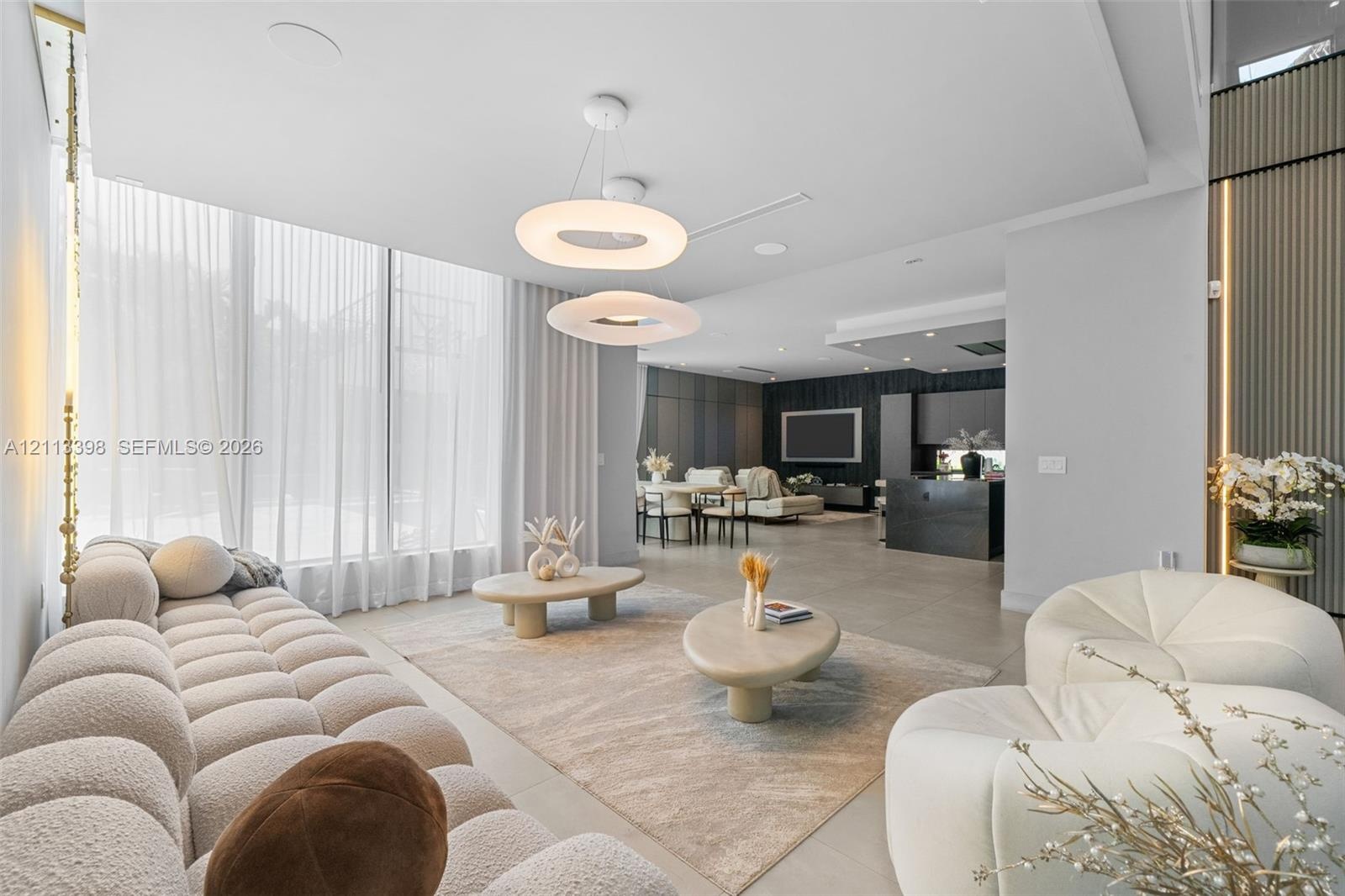 Open-concept interior featuring floor-to-ceiling windows, modern circular pendant lighting, large-format tile flooring, and vertical wall paneling wit