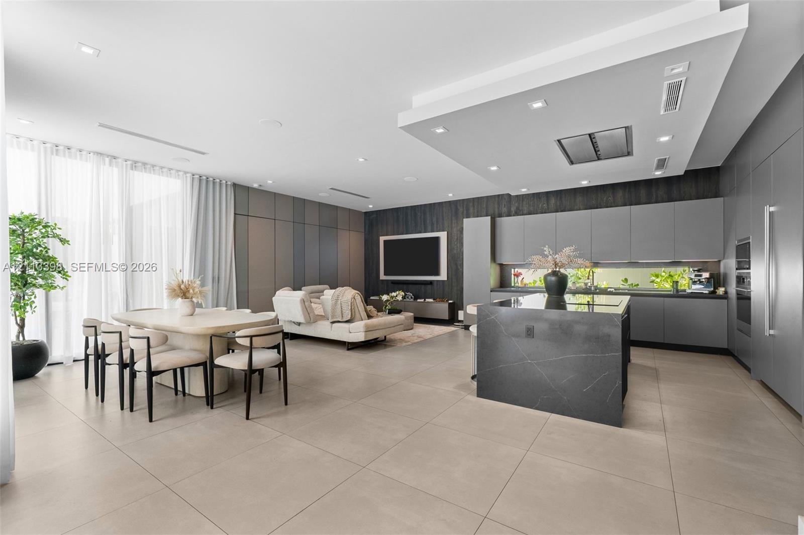 Open-concept interior featuring large-format tile flooring, a kitchen island with stone surfacing, matte-finish cabinetry, recessed ceiling lighting, 