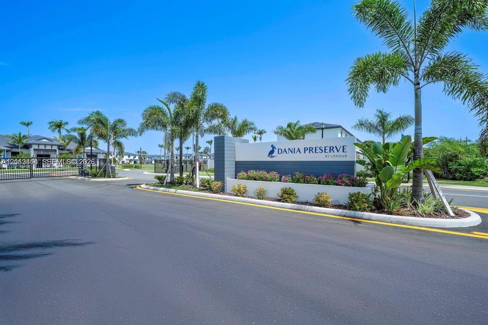 Gated entrance featuring professional hardscaping, manicured landscaping, and mature palm trees
