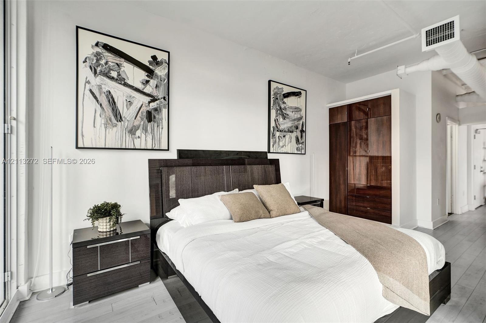 Built-in floor-to-ceiling dark wood cabinetry, white wood-finish flooring, and exposed ceiling ductwork