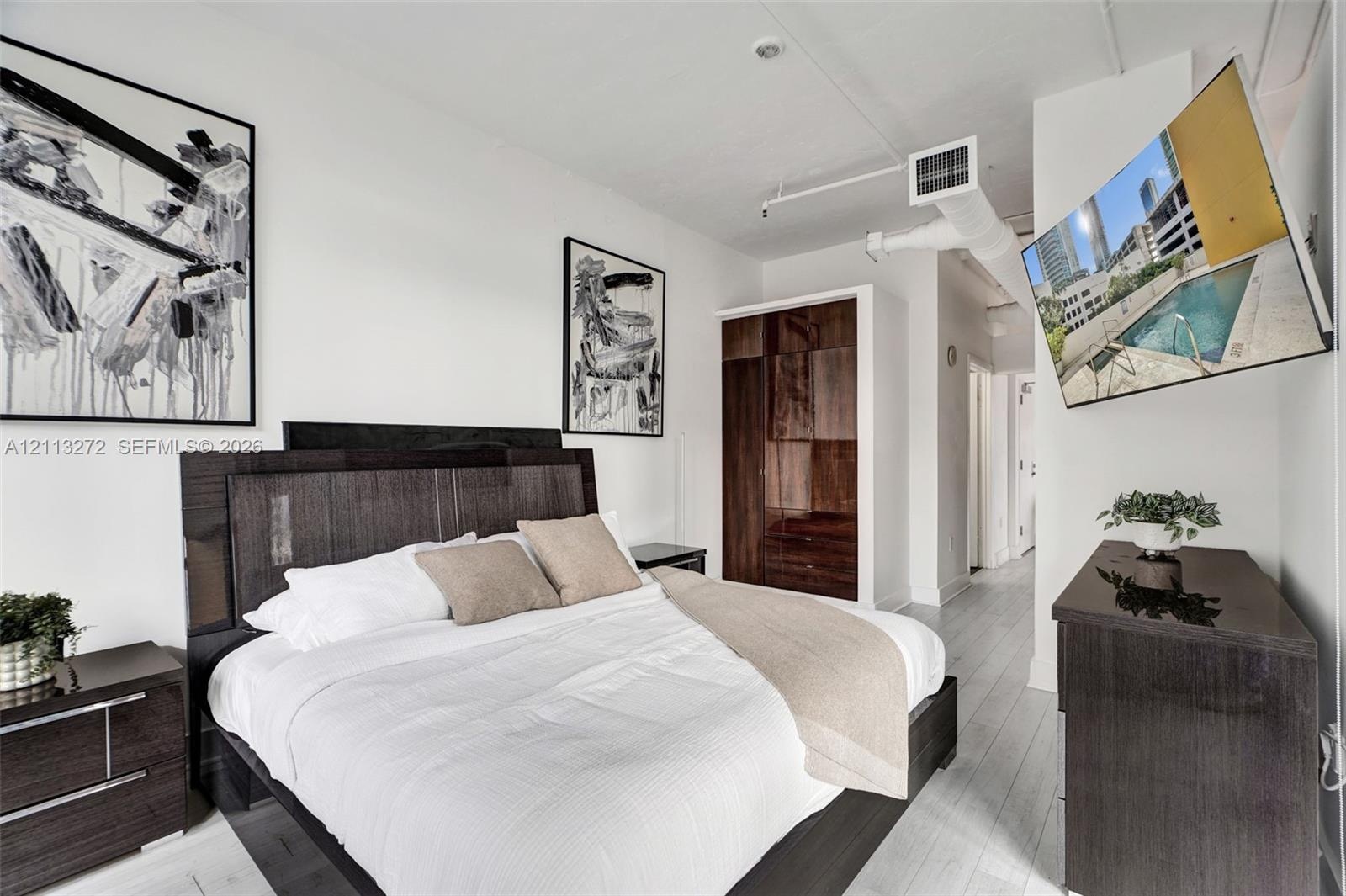 High-ceiling loft featuring exposed ductwork, white wood-finish flooring, and built-in dark wood cabinetry