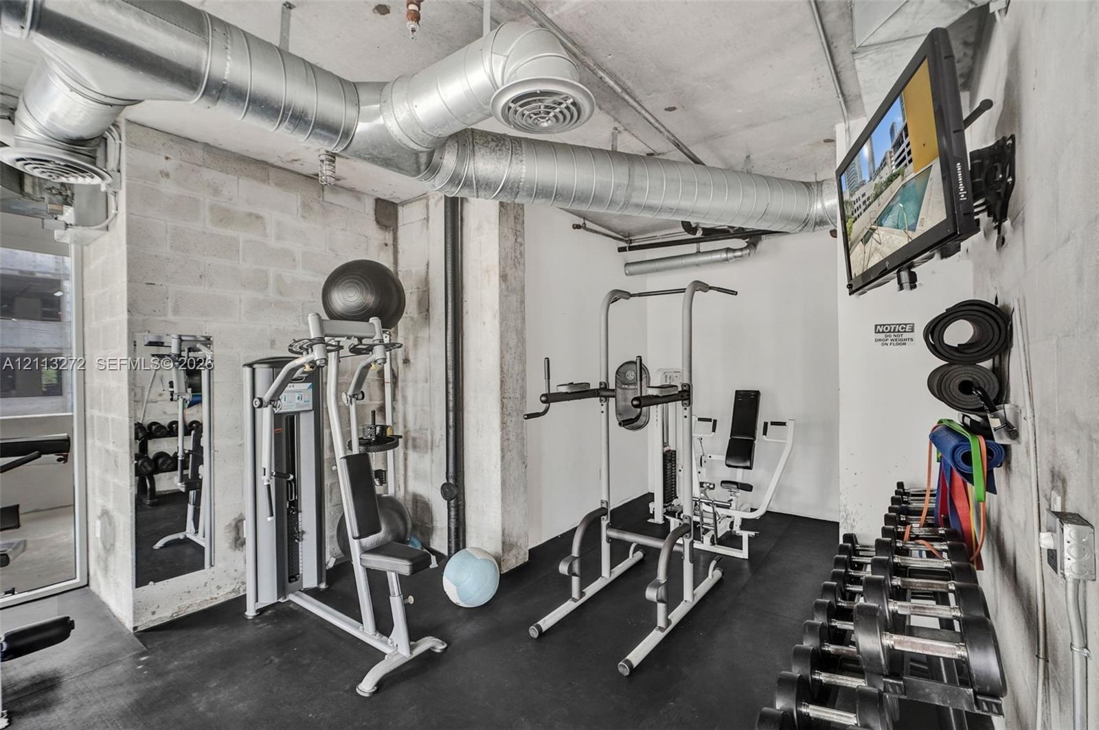 Industrial-style interior featuring exposed concrete masonry unit walls, exposed galvanized steel ductwork, and black rubberized flooring
