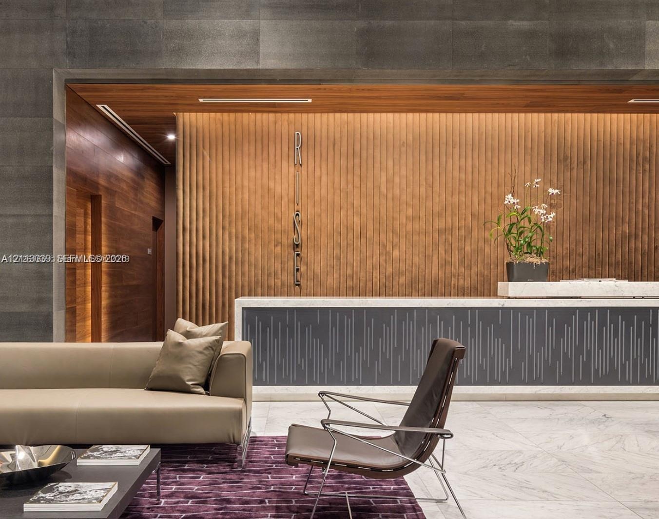 Reception area featuring large-format dark stone wall cladding, vertical wood-slat paneling, stone flooring, and a bespoke reception desk with integra