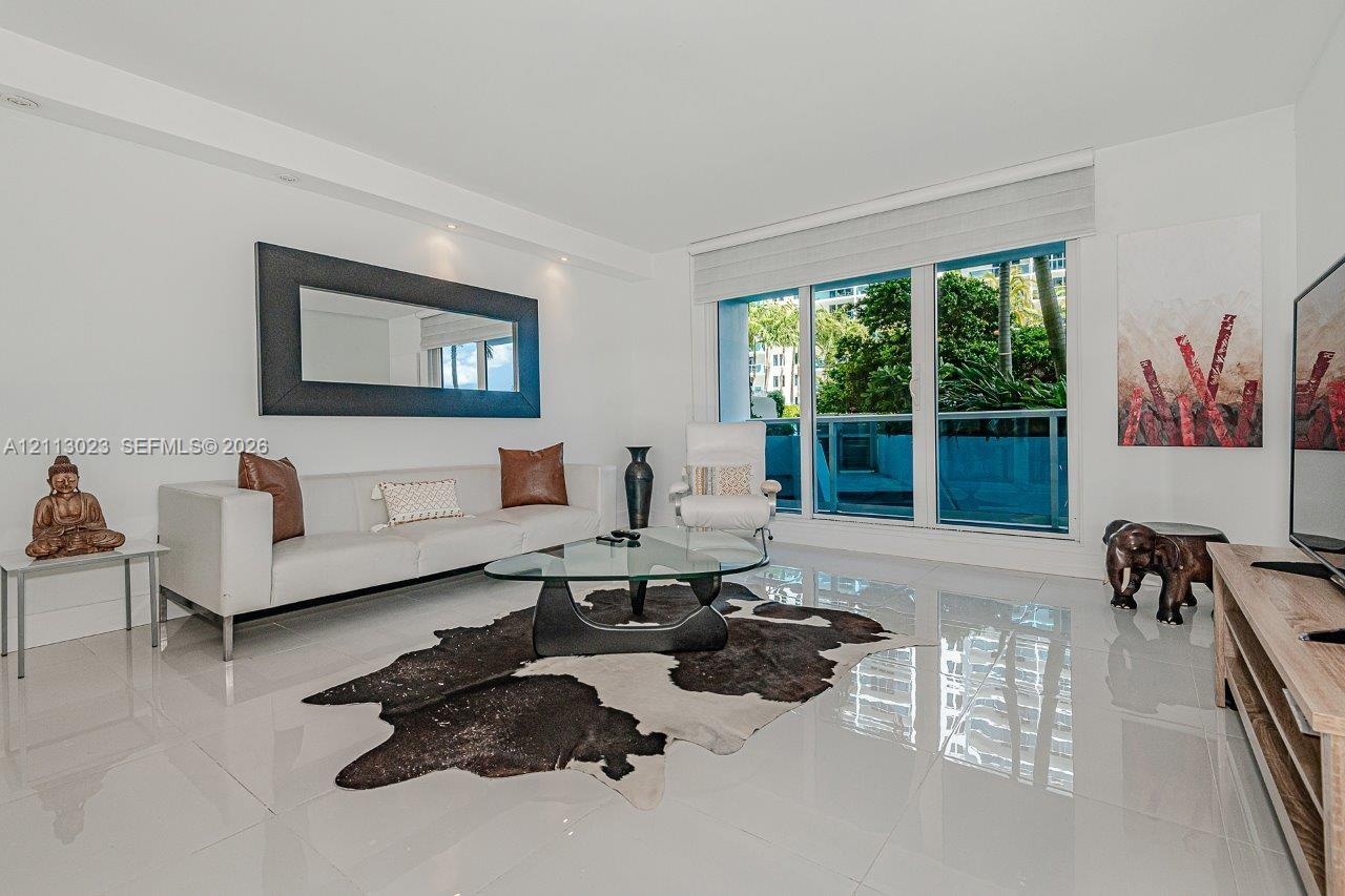 Living area featuring large-format tile flooring, recessed ceiling lighting, and expansive floor-to-ceiling glass sliding doors opening to a balcony