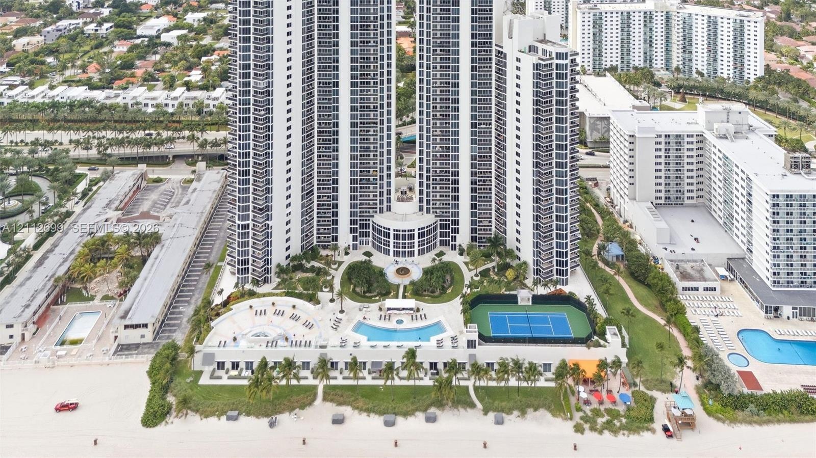 High-rise residential tower featuring a direct beachfront location, swimming pool with surrounding deck, tennis court, and professionally landscaped g
