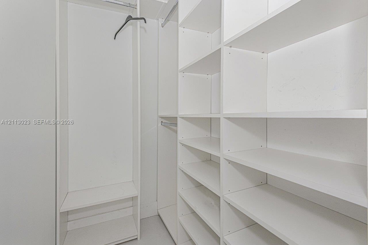 Built-in storage closet featuring white shelving units and integrated metal clothing rods