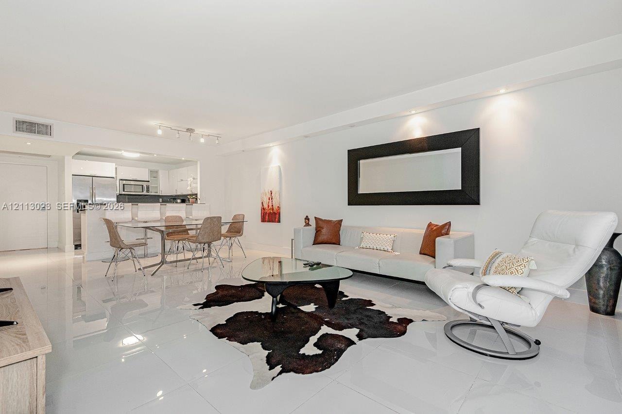 Open-concept living space featuring high-gloss tile flooring, recessed ceiling lighting, and a breakfast bar with stone-finish countertops