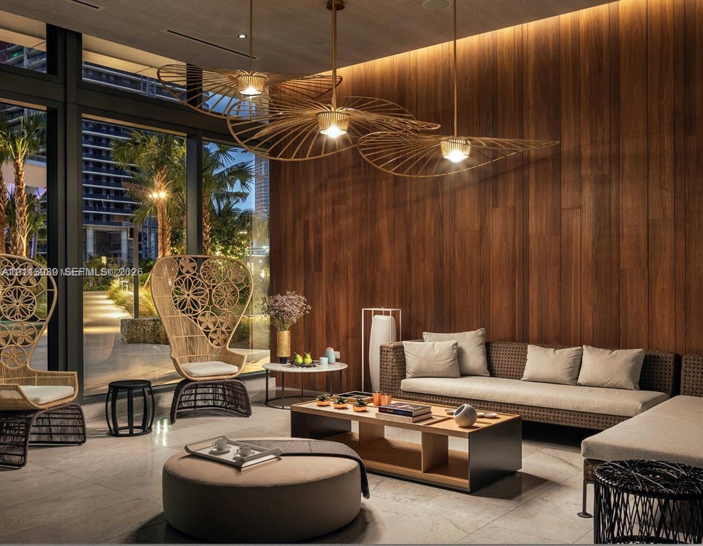 Floor-to-ceiling windows, natural wood-paneled walls, large-scale sculptural metal pendant lighting, and polished stone flooring