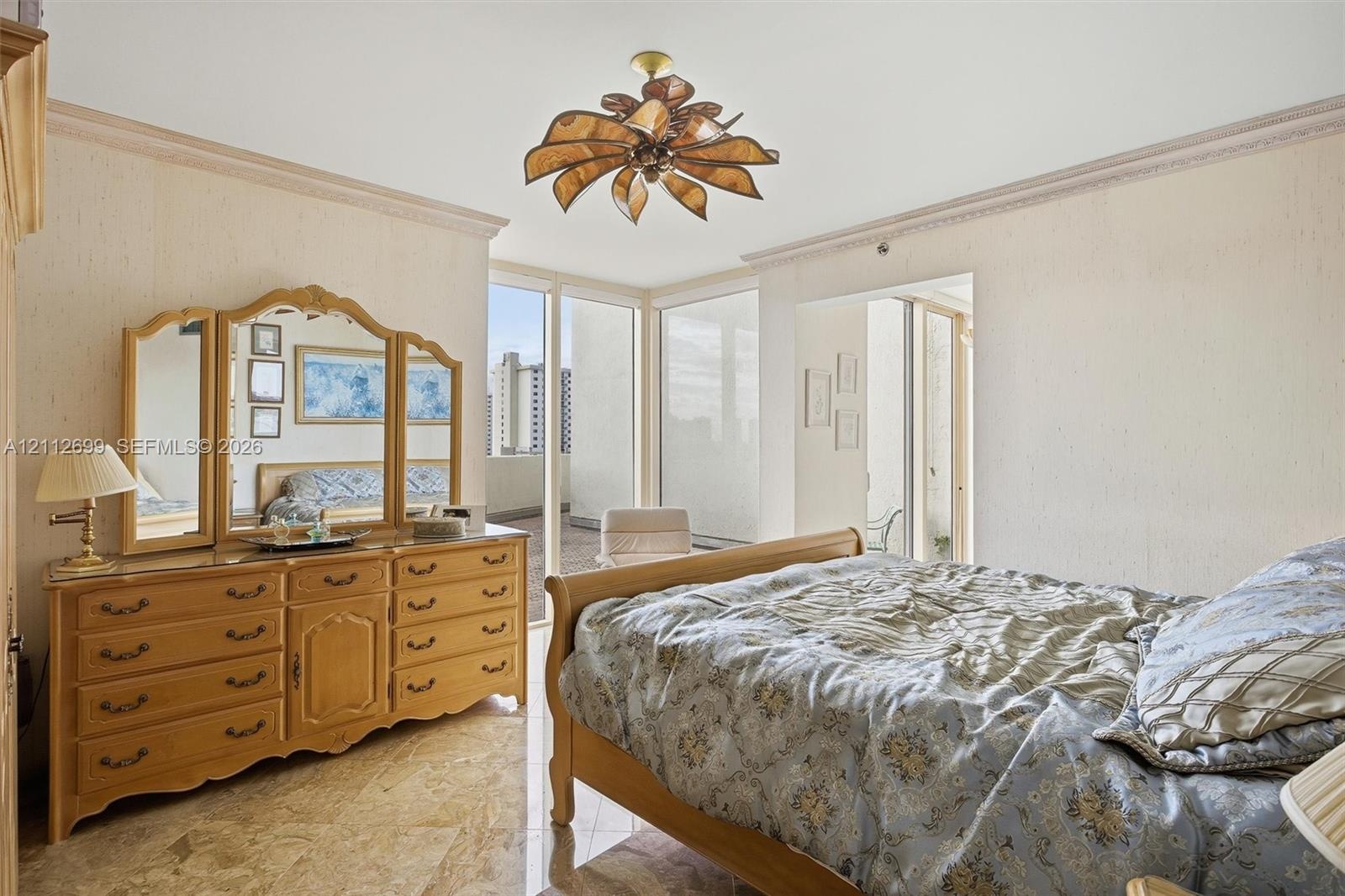 Floor-to-ceiling windows, polished stone flooring, intricate crown molding, and a decorative petal-style ceiling fixture