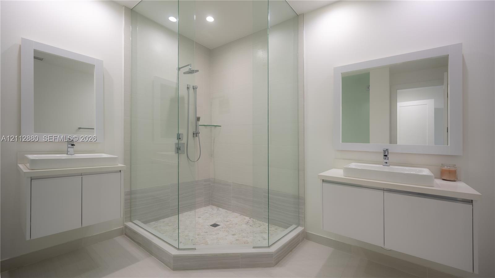 Dual floating vanities featuring rectangular vessel sinks and white cabinetry, paired with a glass-enclosed shower with polished chrome fixtures and t