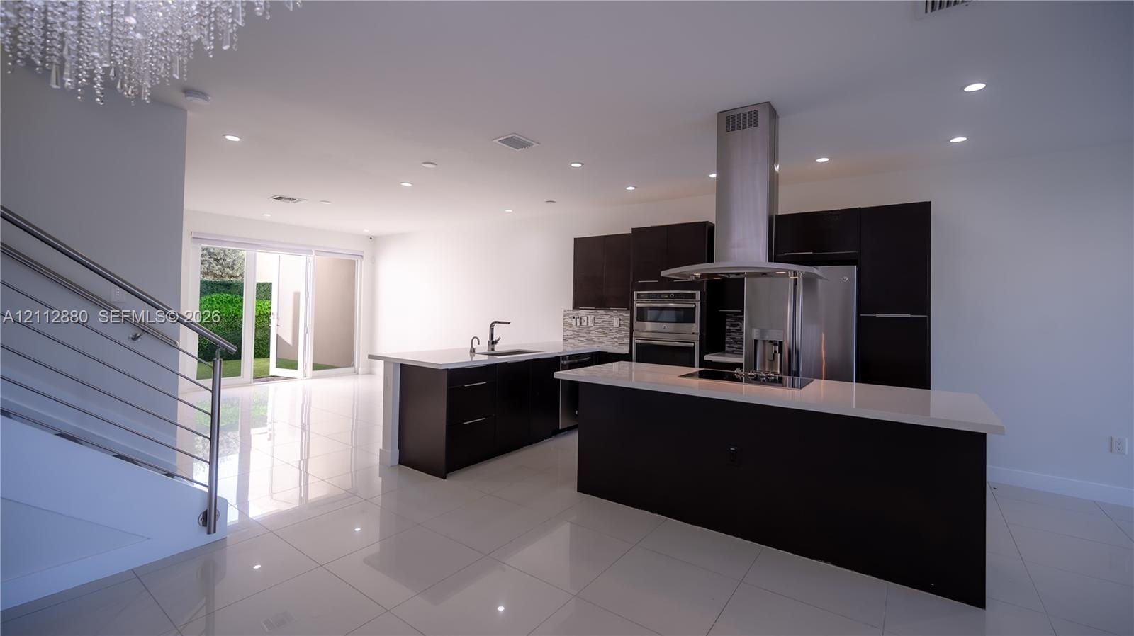 Kitchen featuring dark cabinetry, quartz countertops, a stainless steel range hood, built-in wall oven, and polished tile flooring