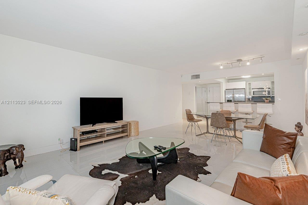 Open floor plan featuring polished tile flooring, recessed lighting, and a kitchen breakfast bar
