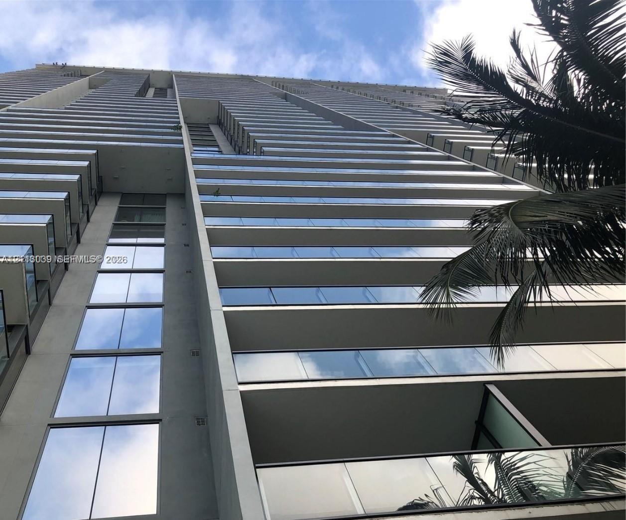 High-rise architectural exterior featuring glass-paneled balconies, concrete structural elements, and floor-to-ceiling windows