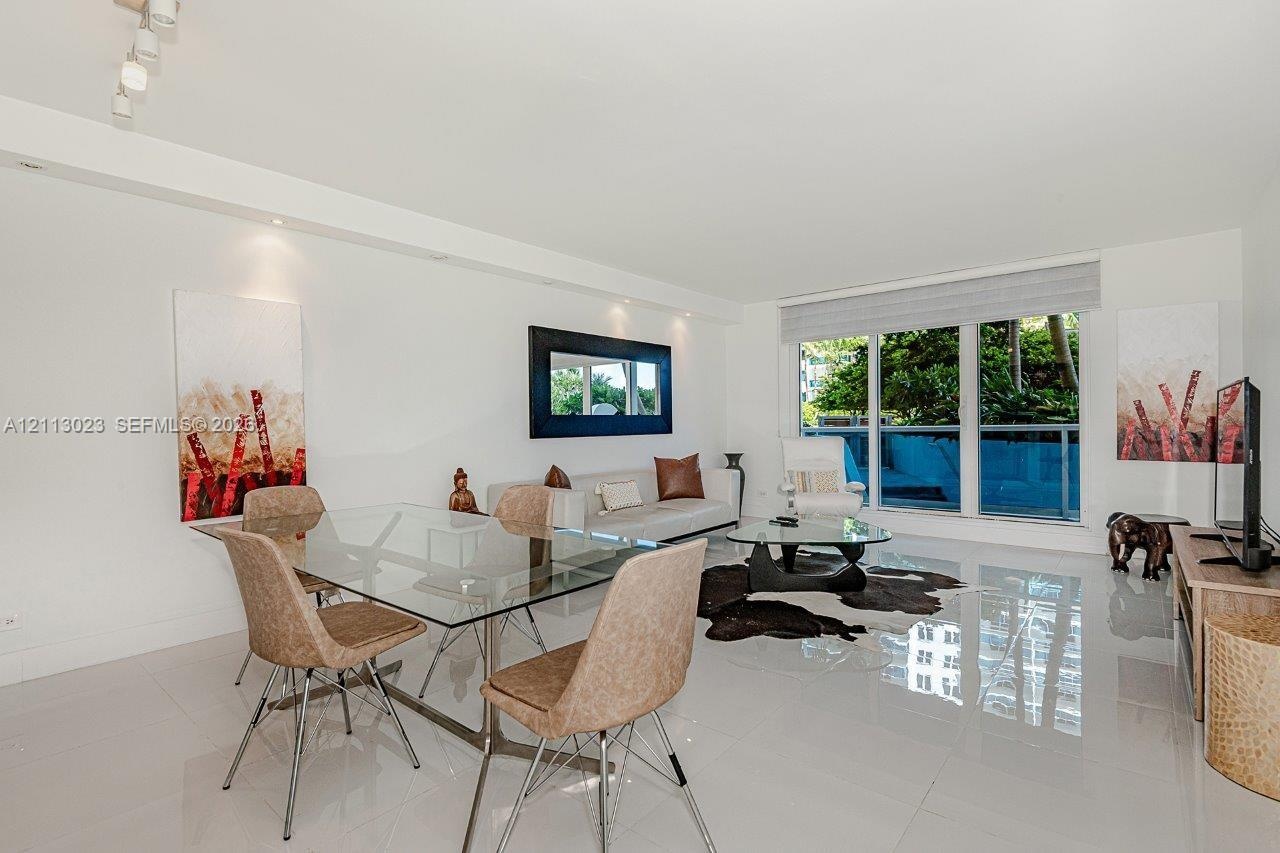 Open-concept living space featuring high-gloss tile flooring, floor-to-ceiling glass paneling, recessed lighting, and integrated track lighting