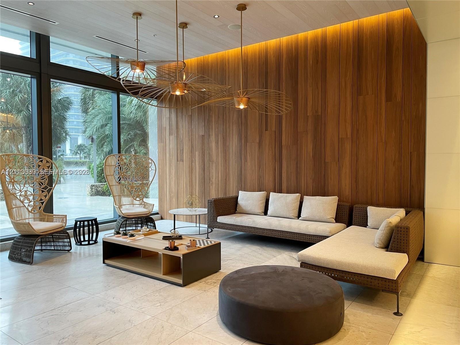 Floor-to-ceiling glass windows, wood-paneled accent wall, recessed perimeter lighting, large-format tile flooring, and metallic architectural pendant 