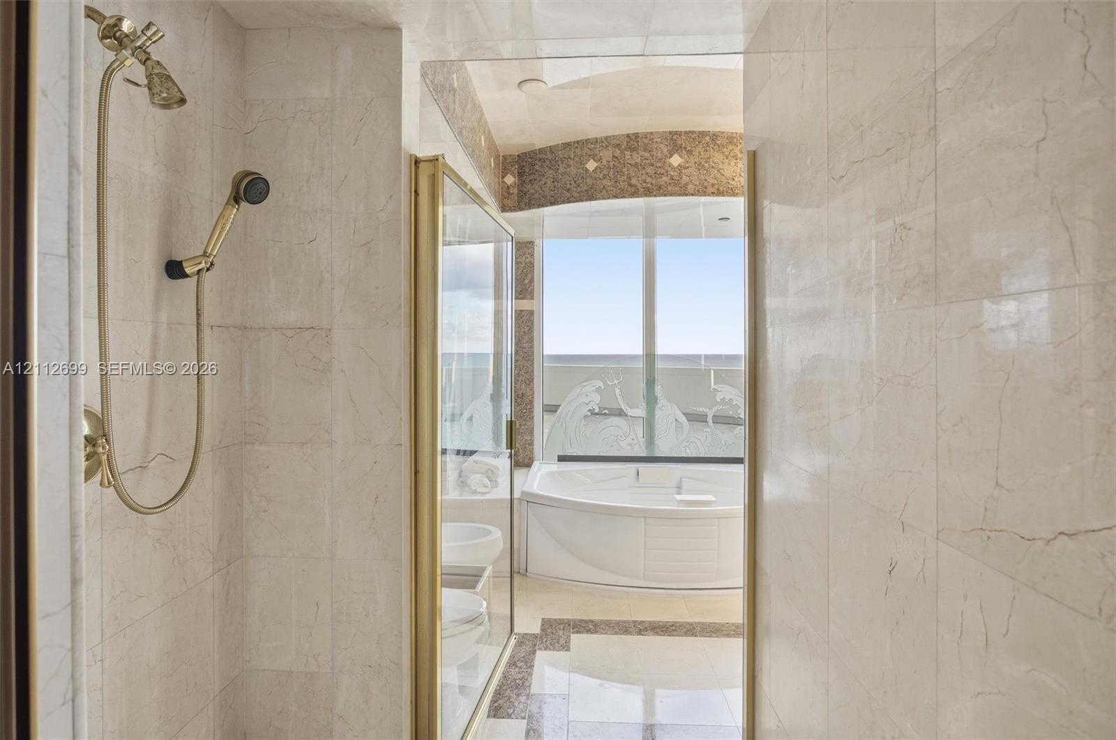 Stone-tiled shower connects two bathrooms in the primary bedroom.