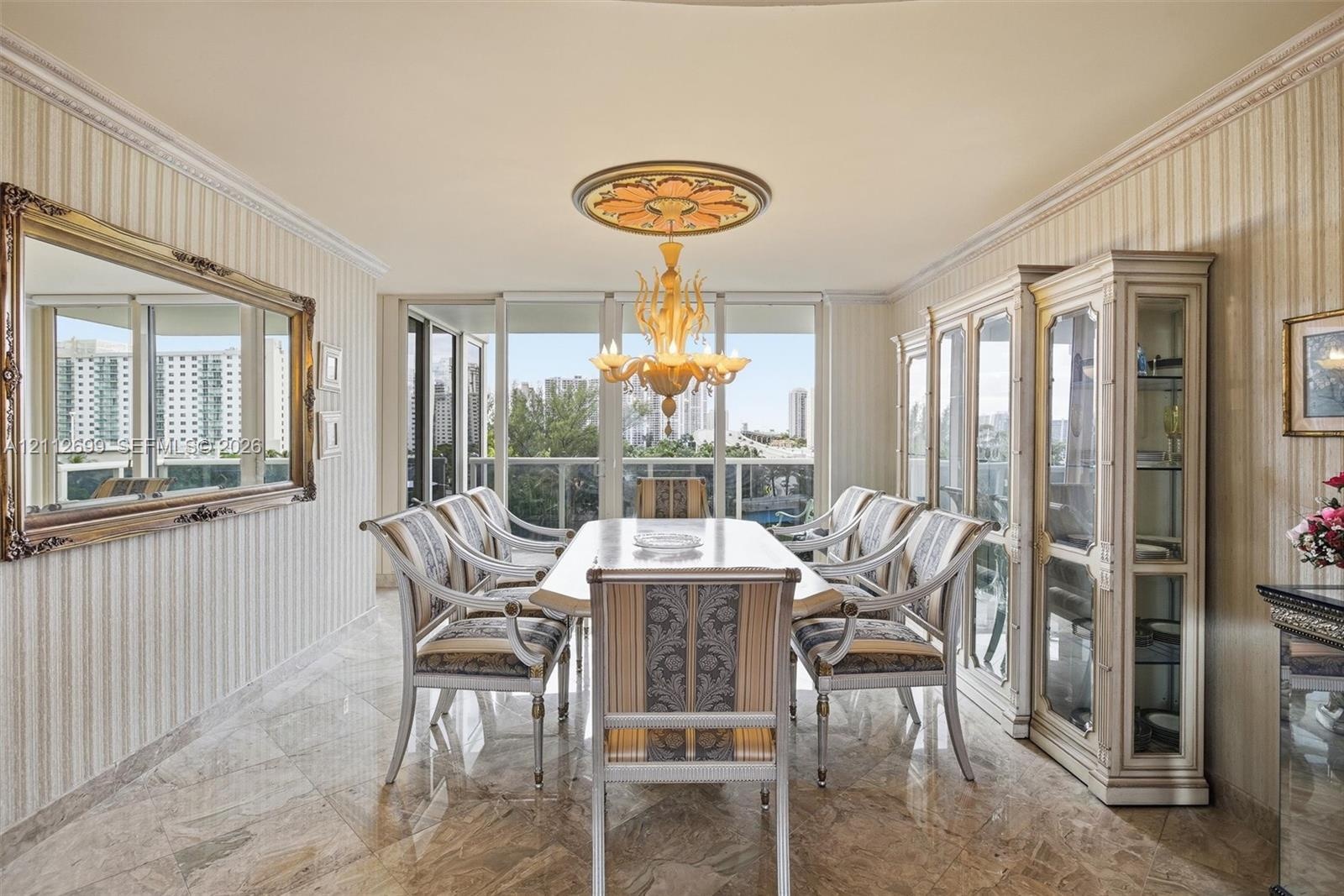 Dining area featuring polished stone flooring, custom built-in cabinetry, crown molding, a decorative ceiling medallion, and a chandelier