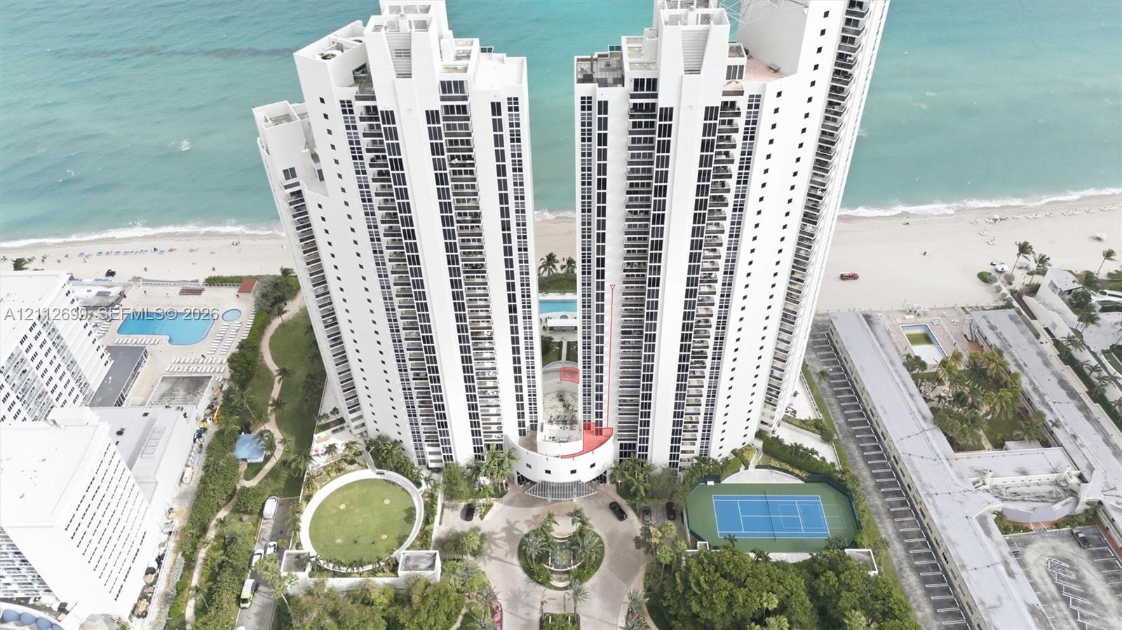 High-rise residential towers featuring beachfront access, a multi-court tennis facility, and a swimming pool