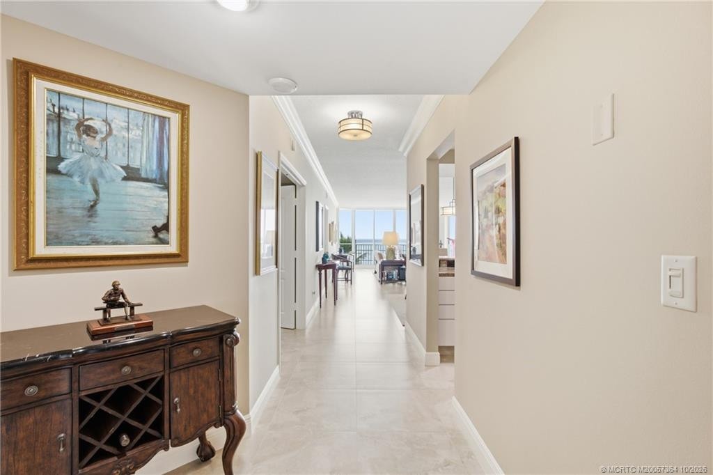 Spacious entry hallway with neutral tile flooring, crown molding, and a beautiful view straight through to the Atlantic Ocean.