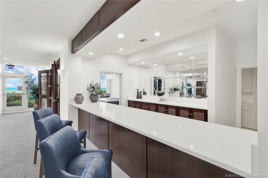 Stylish bar area with countertop seating, rich wood cabinetry, and a convenient location adjacent to the oceanfront social room.