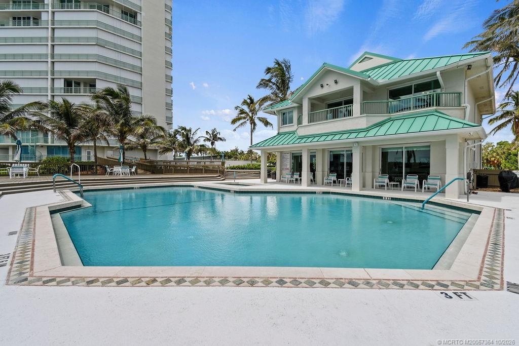 Beautiful resort-style pool area featuring a convenient poolside building with indoor facilities, restrooms, and an outdoor shower.