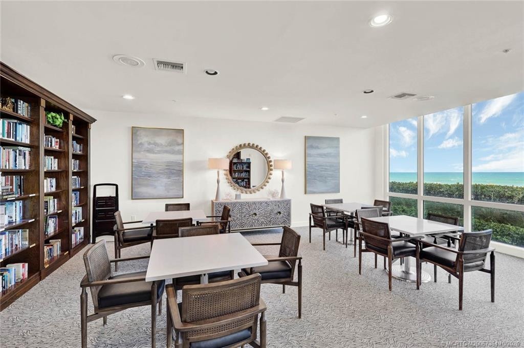 Beautifully furnished card and game room featuring multiple tables, comfortable seating, and panoramic ocean views.