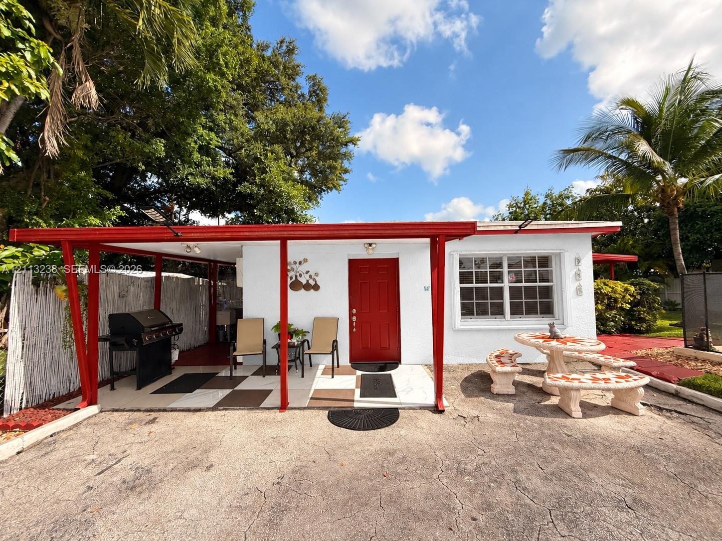 Exterior facade featuring a covered patio, red-painted structural supports, a bold red entry door, and multi-pane window glazing