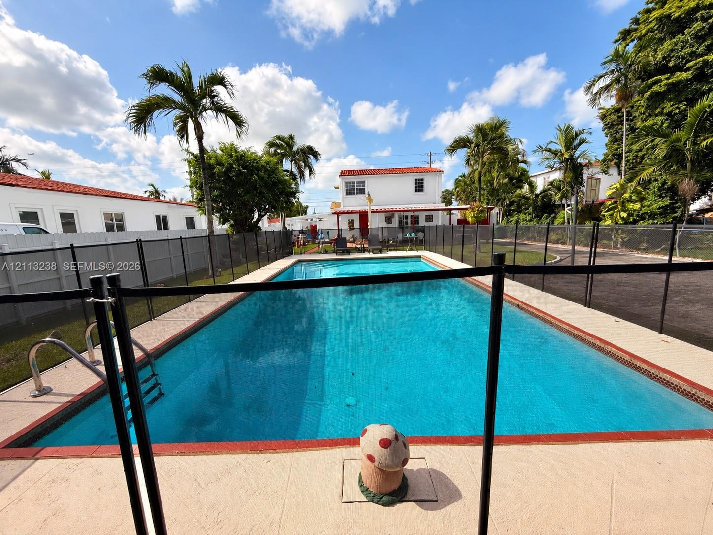 In-ground swimming pool featuring a tiled perimeter and metal safety fencing set within a concrete deck