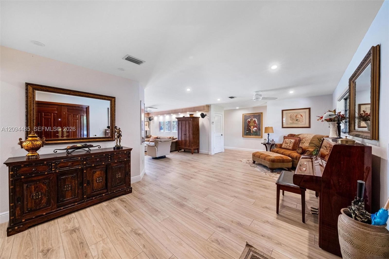 Open-concept interior featuring light-toned wood-finish flooring, recessed lighting, and dual-door entry